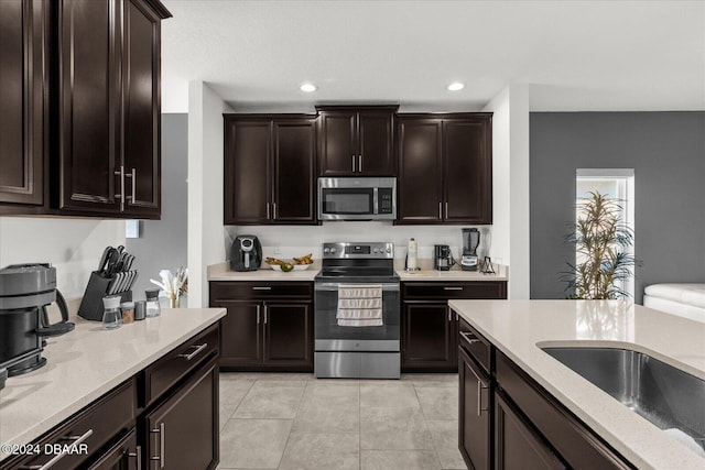 kitchen with sink, dark brown cabinets, light tile patterned floors, and appliances with stainless steel finishes