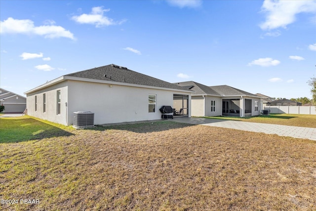 rear view of house featuring a sunroom, a yard, and central AC