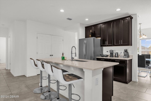 kitchen with stainless steel fridge, sink, decorative light fixtures, a chandelier, and an island with sink