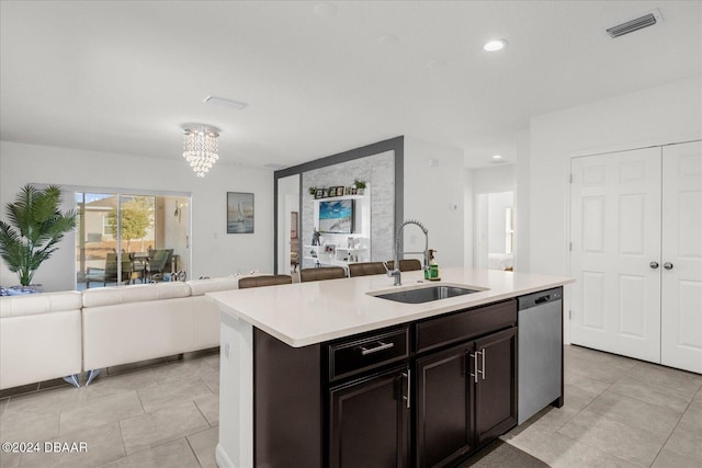 kitchen with a kitchen island with sink, sink, stainless steel dishwasher, a notable chandelier, and light tile patterned flooring