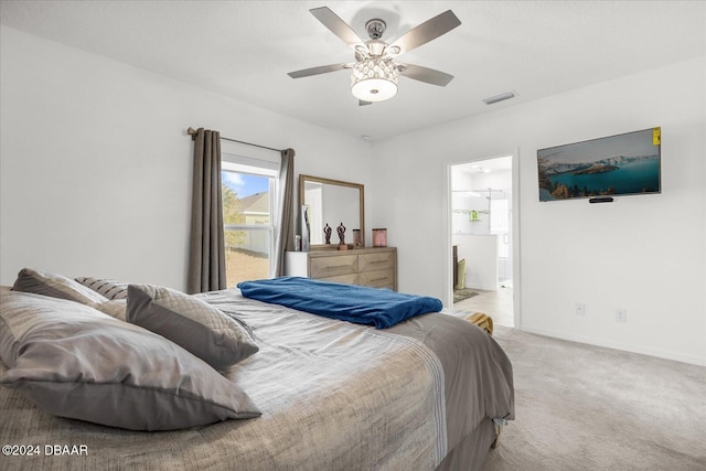 bedroom with ceiling fan, light colored carpet, and ensuite bathroom