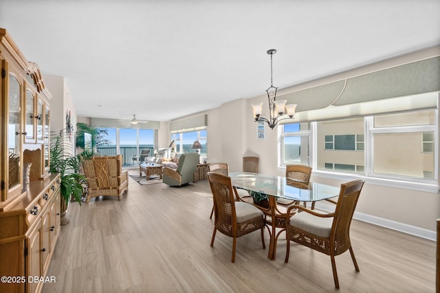 dining area featuring ceiling fan with notable chandelier and light hardwood / wood-style floors