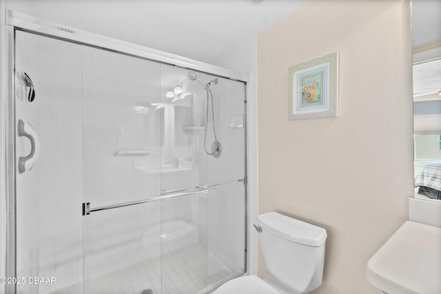 bathroom with toilet and a shower with shower door