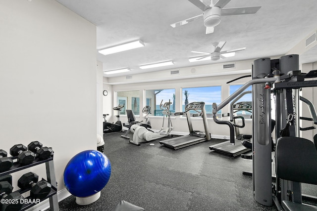 workout area with ceiling fan and a textured ceiling