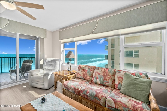 living room featuring light wood-type flooring, ceiling fan, and a water view