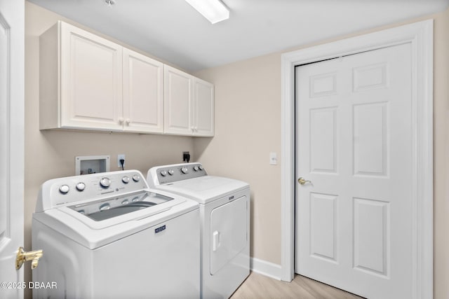 clothes washing area featuring cabinets, light hardwood / wood-style floors, and washer and dryer