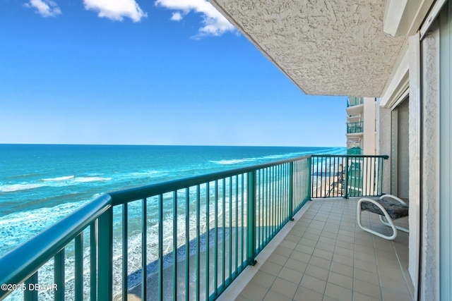 balcony with a water view and a view of the beach