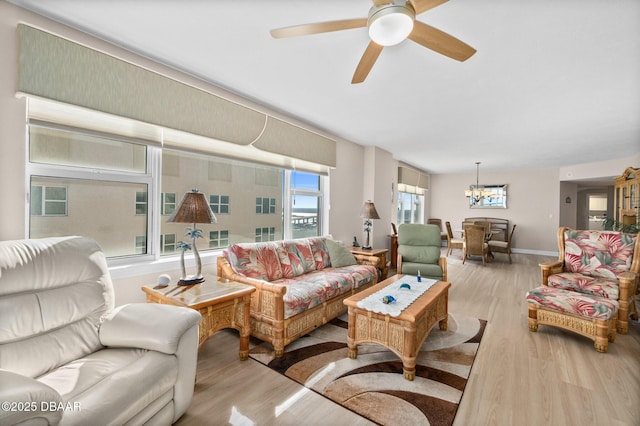 living room with ceiling fan with notable chandelier and light hardwood / wood-style flooring