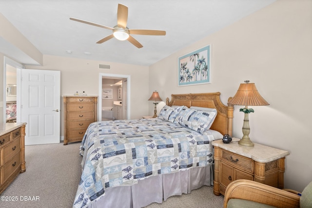 bedroom featuring ceiling fan, light colored carpet, and ensuite bathroom