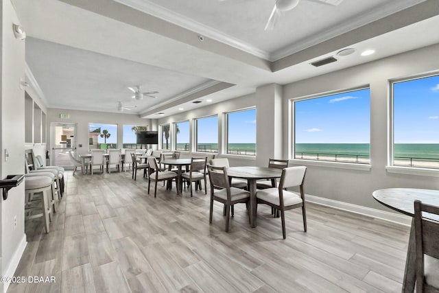 dining room featuring ceiling fan, ornamental molding, a raised ceiling, and light hardwood / wood-style flooring