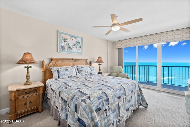 carpeted bedroom with access to exterior, ceiling fan, and a water view