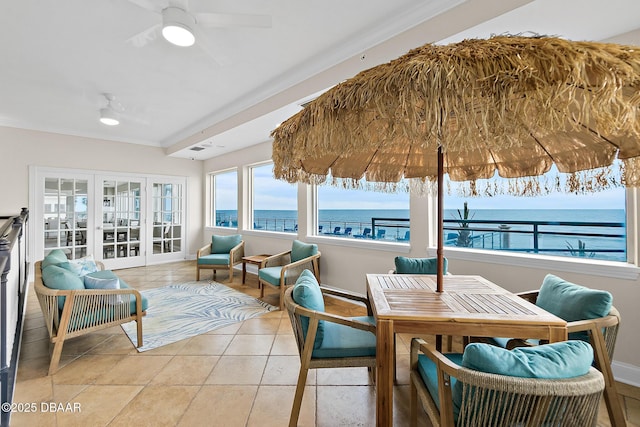 sunroom featuring a water view, ceiling fan, and french doors