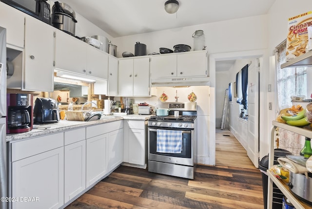 kitchen featuring stainless steel range with gas cooktop, under cabinet range hood, white cabinetry, and dark wood finished floors