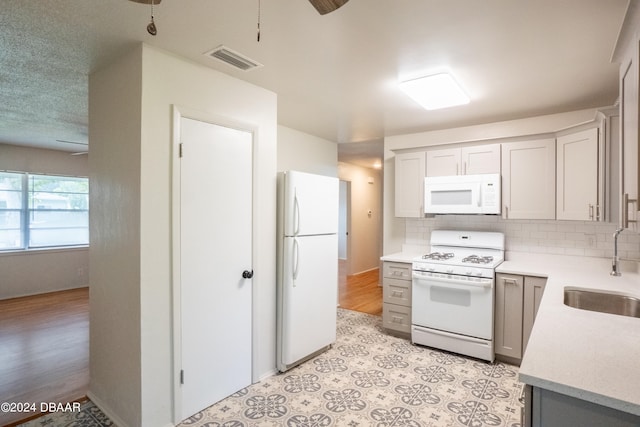 kitchen with tasteful backsplash, sink, white appliances, and light wood-type flooring