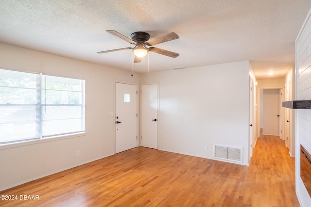 empty room with ceiling fan, light hardwood / wood-style flooring, and a textured ceiling