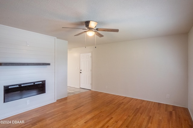 unfurnished living room featuring ceiling fan, wood-type flooring, and a textured ceiling