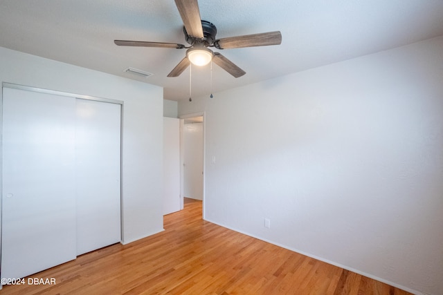 unfurnished bedroom with ceiling fan, light wood-type flooring, and a closet