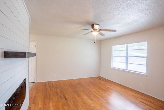 unfurnished living room with a large fireplace, light hardwood / wood-style floors, and a textured ceiling