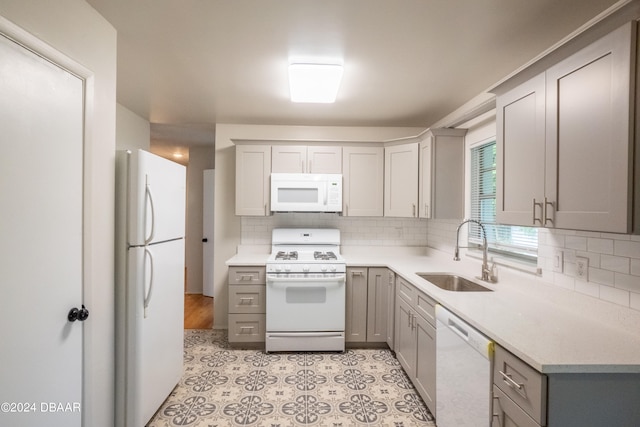 kitchen with backsplash, gray cabinets, sink, and white appliances