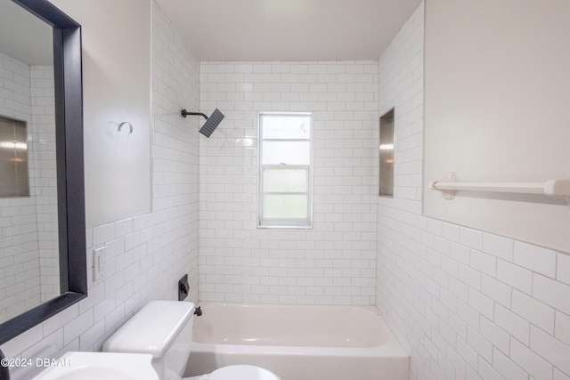 bathroom with toilet, tile walls, and tiled shower / bath