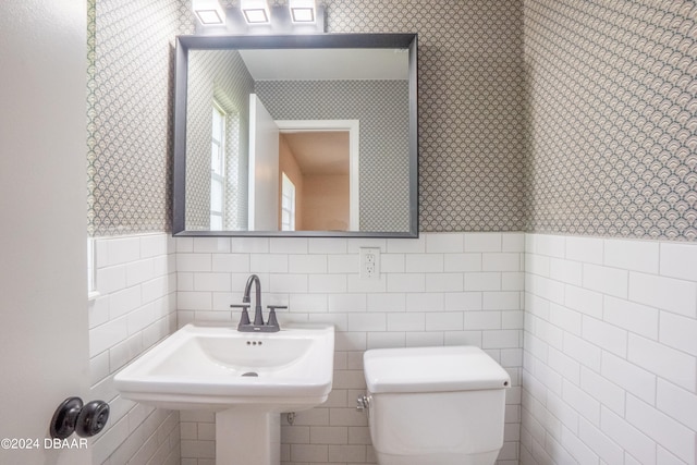 bathroom with sink, toilet, and tile walls