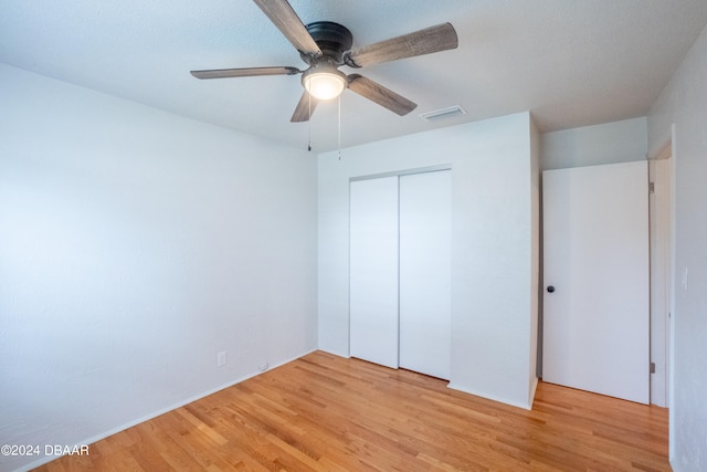 unfurnished bedroom featuring ceiling fan, a closet, and light wood-type flooring