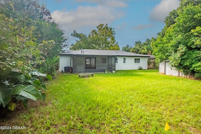 rear view of house featuring a sunroom, a shed, cooling unit, and a lawn