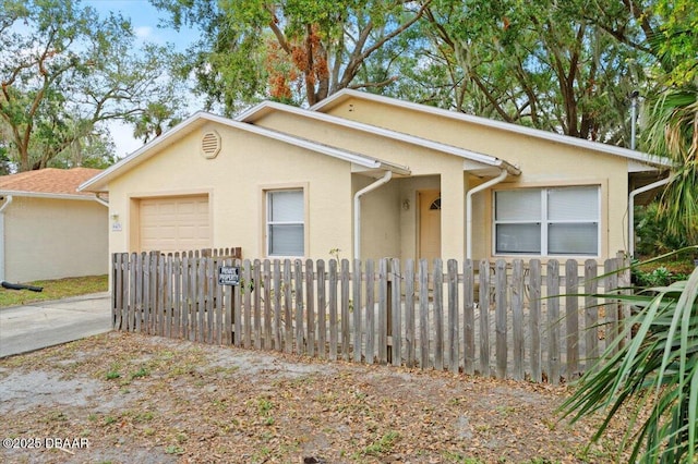 view of front of property featuring a fenced front yard, concrete driveway, an attached garage, and stucco siding