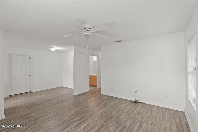 unfurnished room featuring ceiling fan, wood finished floors, visible vents, and baseboards