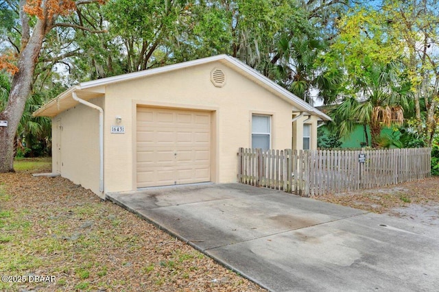 detached garage featuring fence and driveway