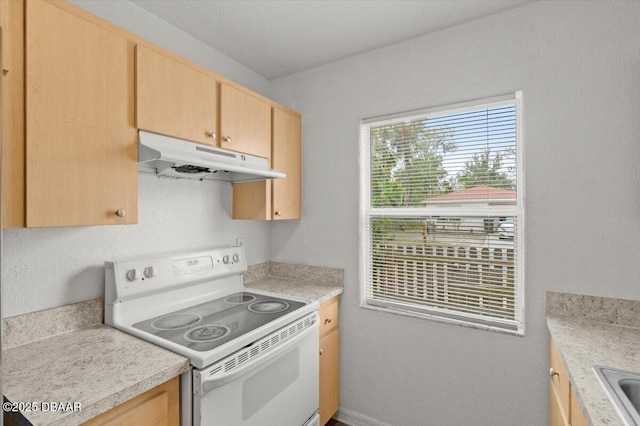 kitchen with under cabinet range hood, electric range, light brown cabinets, and light countertops