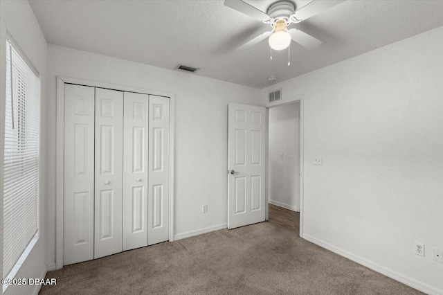 unfurnished bedroom featuring carpet floors, baseboards, visible vents, and a closet