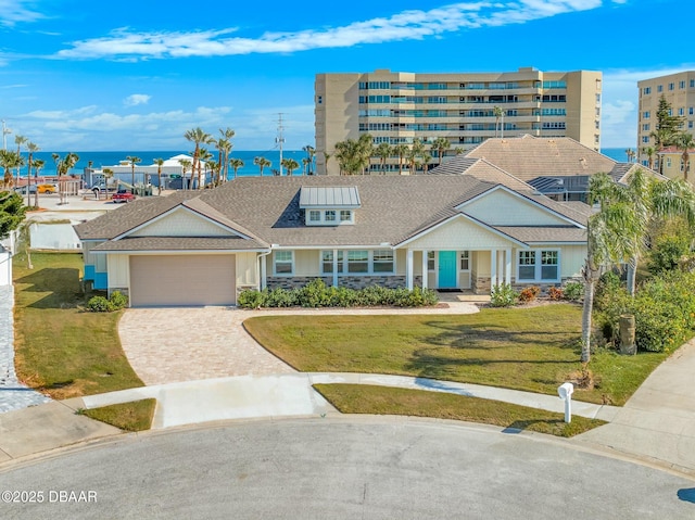 view of front of house featuring a garage, a front lawn, and a water view