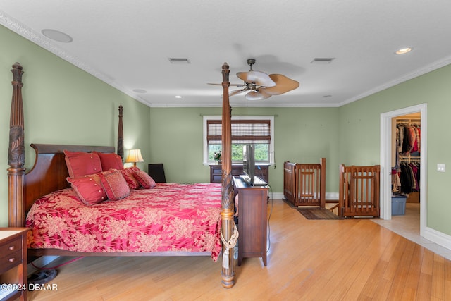 bedroom featuring light hardwood / wood-style floors, ceiling fan, crown molding, a closet, and a spacious closet