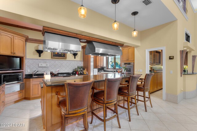 kitchen featuring appliances with stainless steel finishes, backsplash, a center island, wall chimney range hood, and exhaust hood