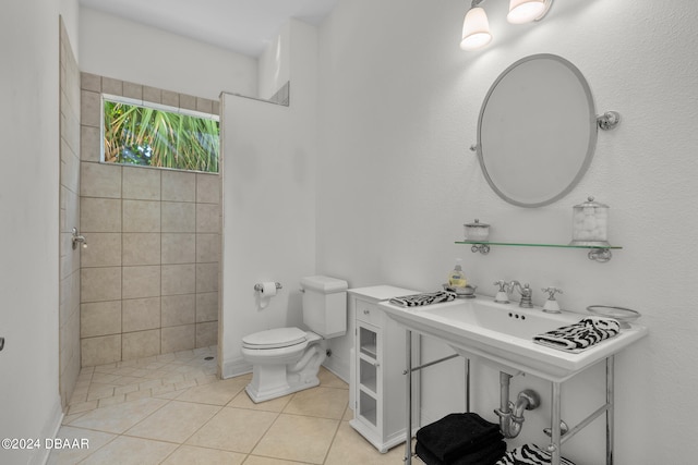 bathroom with toilet, a tile shower, and tile patterned floors