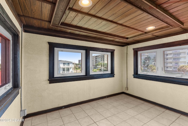 tiled empty room featuring wooden ceiling and beam ceiling