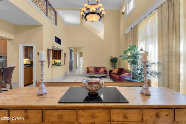 kitchen with a towering ceiling, stainless steel oven, an inviting chandelier, and ornamental molding