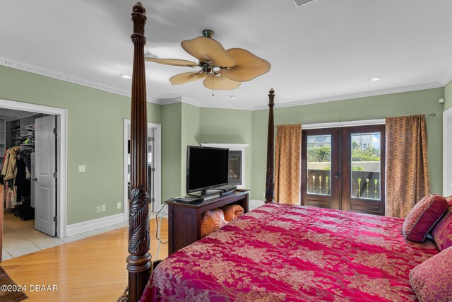 bedroom featuring a walk in closet, crown molding, light wood-type flooring, access to exterior, and ceiling fan