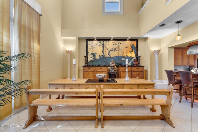 dining area featuring light tile patterned floors and a towering ceiling