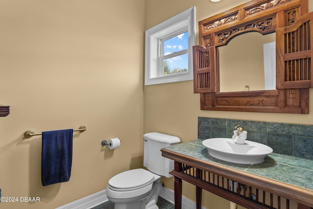 bathroom with toilet, tasteful backsplash, and sink