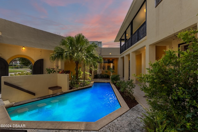 pool at dusk featuring a patio area