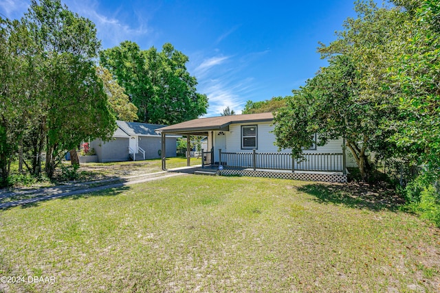 1318 San Jose Blvd, Daytona Beach, FL 32117 - view of front of home featuring dirt driveway, a porch, a carport, a front lawn, and an outdoor structure