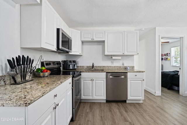 1318 San Jose Blvd, Daytona Beach, FL 32117 - kitchen featuring appliances with stainless steel finishes, a sink, light wood-style floors, white cabinetry, and light stone countertops