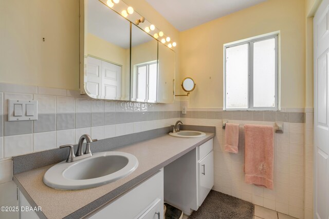 6361 Turtlemound Rd, New Smyrna Beach, FL 32169 - bathroom featuring a sink, tile walls, a wainscoted wall, and double vanity