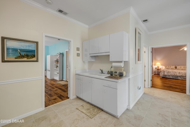 6361 Turtlemound Rd, New Smyrna Beach, FL 32169 - kitchen featuring visible vents, ornamental molding, light countertops, a sink, and light tile patterned floors
