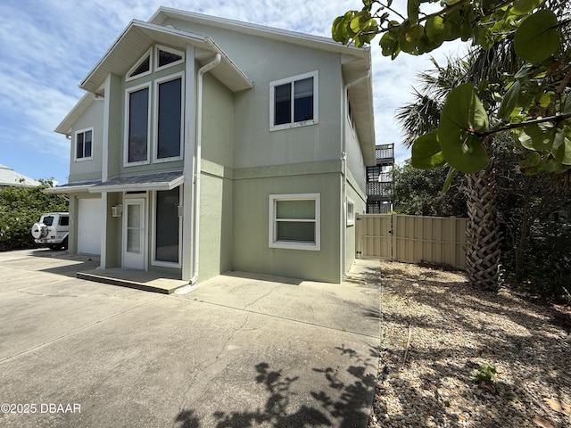 6361 Turtlemound Rd, New Smyrna Beach, FL 32169 - back of property featuring fence, stucco siding, driveway, and a garage
