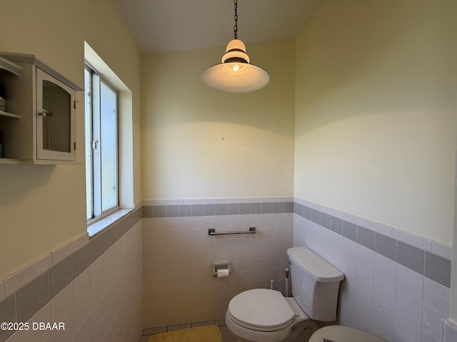 6361 Turtlemound Rd, New Smyrna Beach, FL 32169 - bathroom featuring tile walls, wainscoting, toilet, and a wealth of natural light