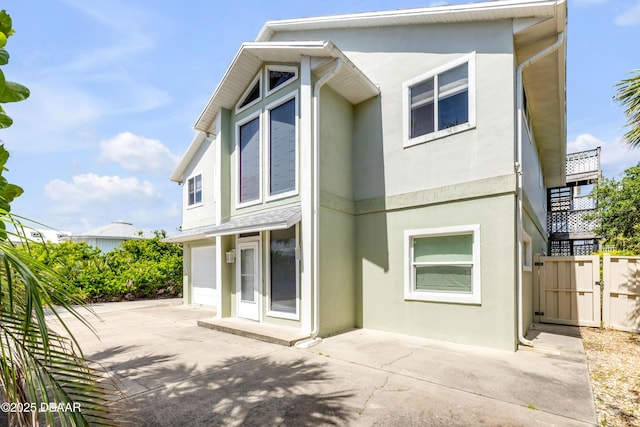 6361 Turtlemound Rd, New Smyrna Beach, FL 32169 - back of house featuring a garage, fence, stucco siding, a gate, and concrete driveway