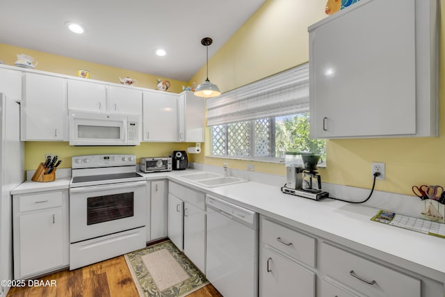 6361 Turtlemound Rd, New Smyrna Beach, FL 32169 - kitchen featuring pendant lighting, wood finished floors, white appliances, white cabinets, and a sink